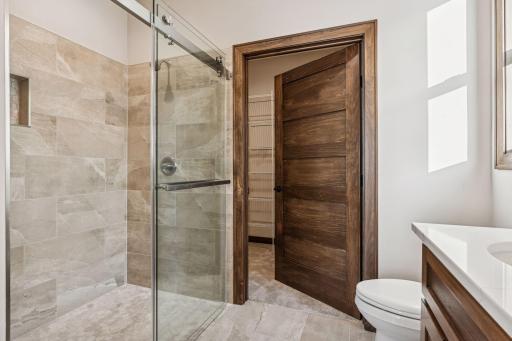 A beautiful tile shower with custom glass door and a huge walk in closet.