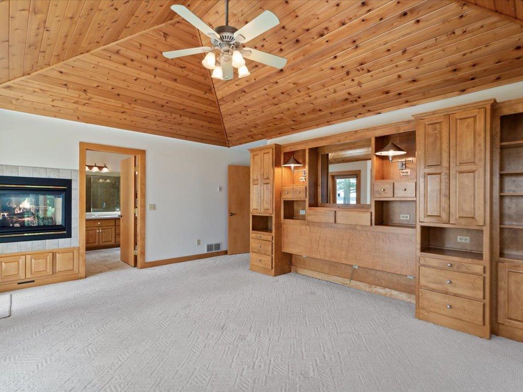 Generous proportions, vaulted knotty pine ceilings, and a cozy fireplace create a private retreat within the main-level primary suite.