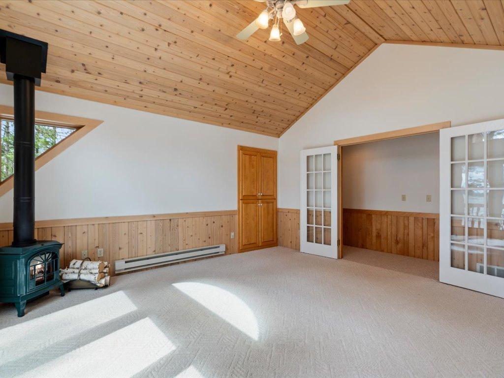 Vaulted wood ceilings and a cozy gas stove create a warm and inviting upper-level bedroom retreat.