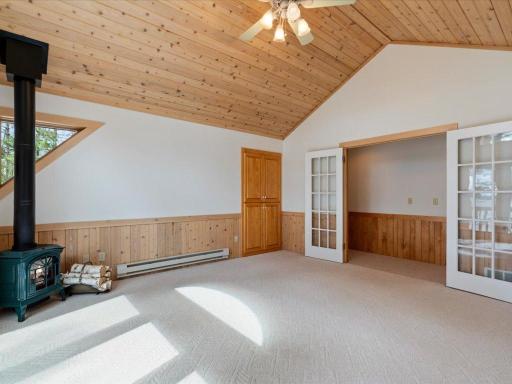 Vaulted wood ceilings and a cozy gas stove create a warm and inviting upper-level bedroom retreat.
