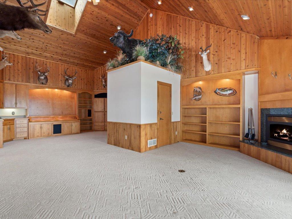 Vaulted wood ceilings, custom built-ins, and a fireplace anchor this expansive family room designed for gathering, relaxing, and entertaining.