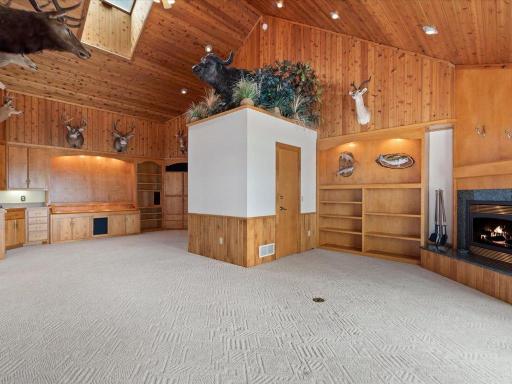 Vaulted wood ceilings, custom built-ins, and a fireplace anchor this expansive family room designed for gathering, relaxing, and entertaining.