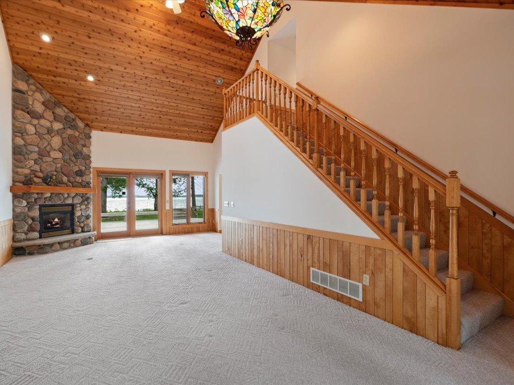 A grand staircase, soaring ceilings, and a floor-to-ceiling stone fireplace create a dramatic introduction to this lakeside retreat.