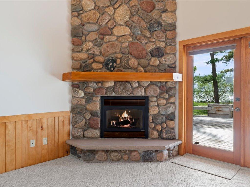 A floor-to-ceiling stone fireplace creates a warm focal point, while deck access extends the living space toward the lake.