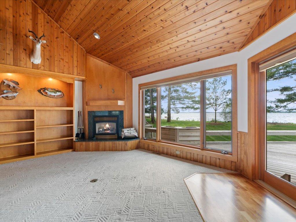 Walls of glass frame Upper Whitefish Lake while a fireplace and lakeside deck create an inviting space for year-round enjoyment.
