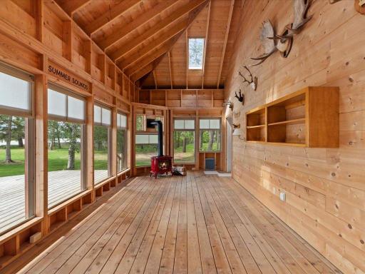 The vaulted three-season porch offers a spectacular setting to enjoy lake breezes, morning coffee, and evenings by the gas fireplace surrounded by nature.