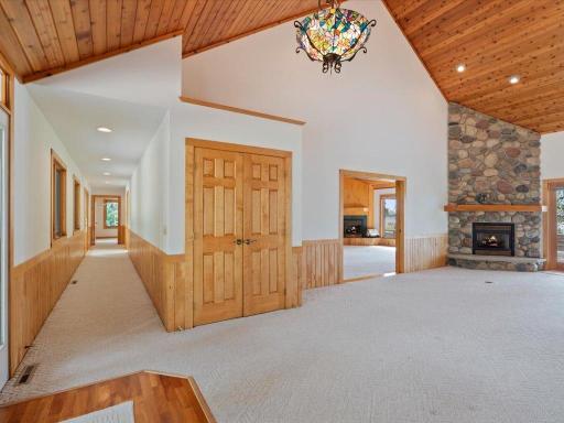 A welcoming foyer opens to the home's expansive living spaces, with a hallway leading to the main-level bedrooms and a stunning stone fireplace anchoring the living room.