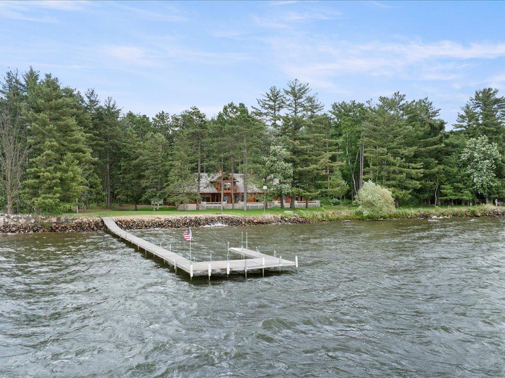 A private dock extends into the lake, while the home rests on 300 feet of shoreline surrounded by towering pines and exceptional privacy.