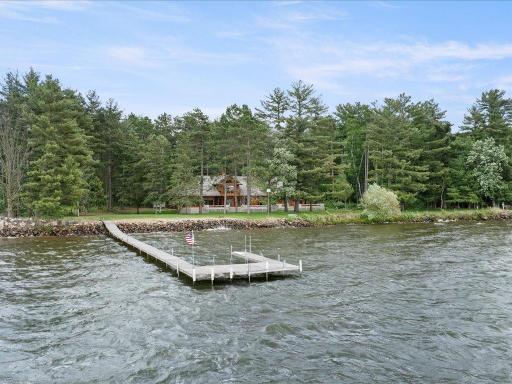 A private dock extends into the lake, while the home rests on 300 feet of shoreline surrounded by towering pines and exceptional privacy.