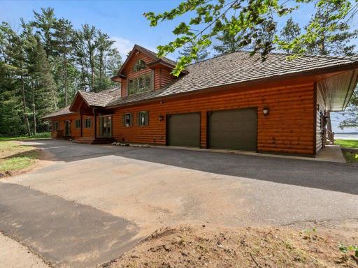 Natural log siding, cedar shake roofing, and an attached garage create a striking first impression upon arrival.
