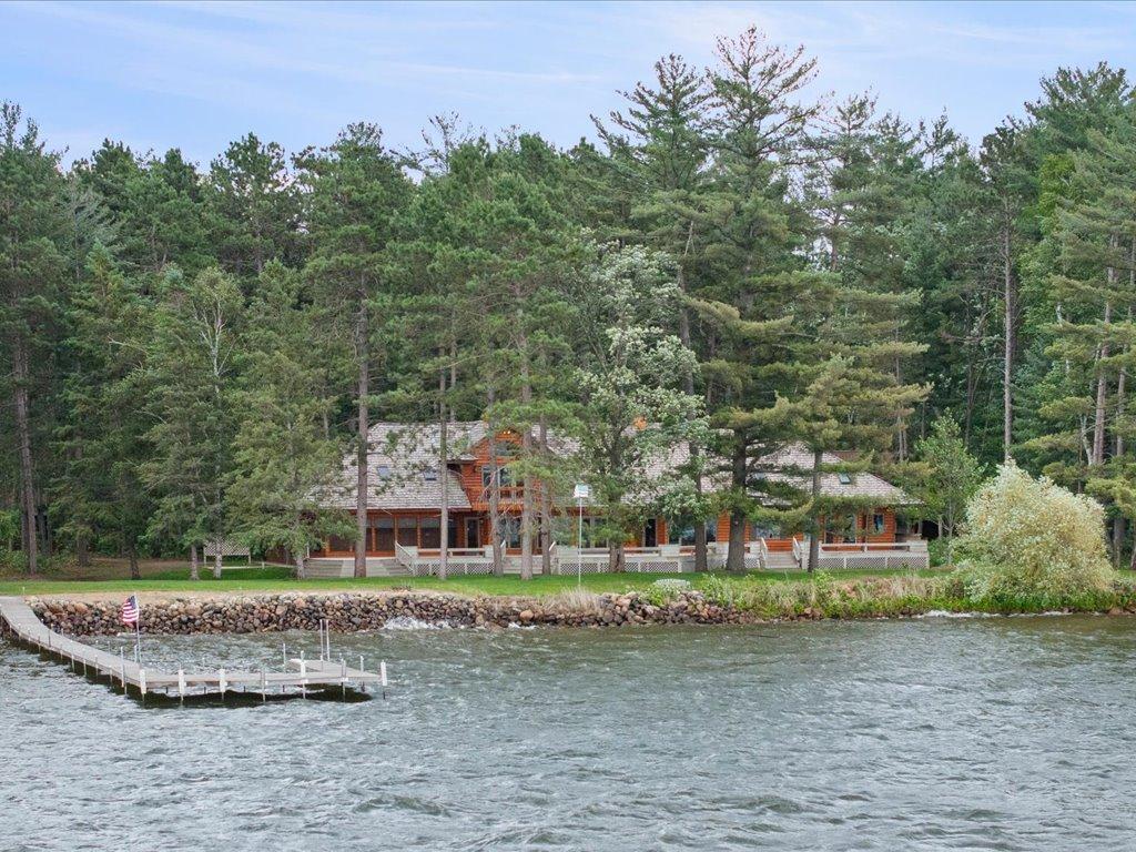 From the water, the estate showcases its impressive scale, expansive lakeside deck, and 300 feet of shoreline framed by mature pines.
