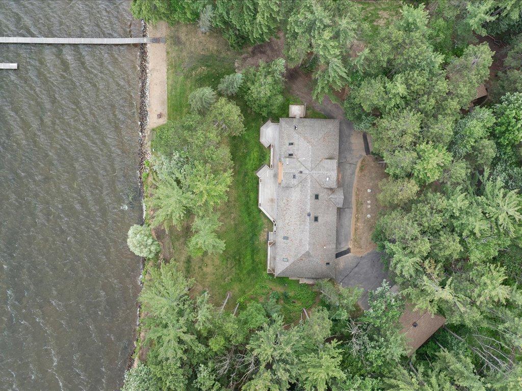 A bird’s-eye view highlights the estate’s private shoreline, dock, and natural setting, with the home nestled among mature pines on the shores of Upper Whitefish Lake.