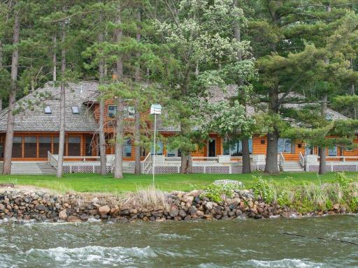 Viewed from the lake, the home blends seamlessly into its wooded setting, offering exceptional privacy, expansive decking, and classic Northwoods charm.