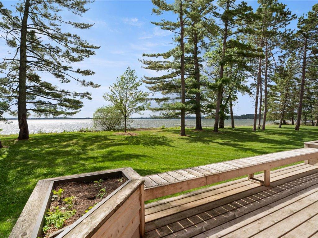 Mature pines, a manicured lakeside lawn, and sweeping water views create a timeless Northwoods setting.