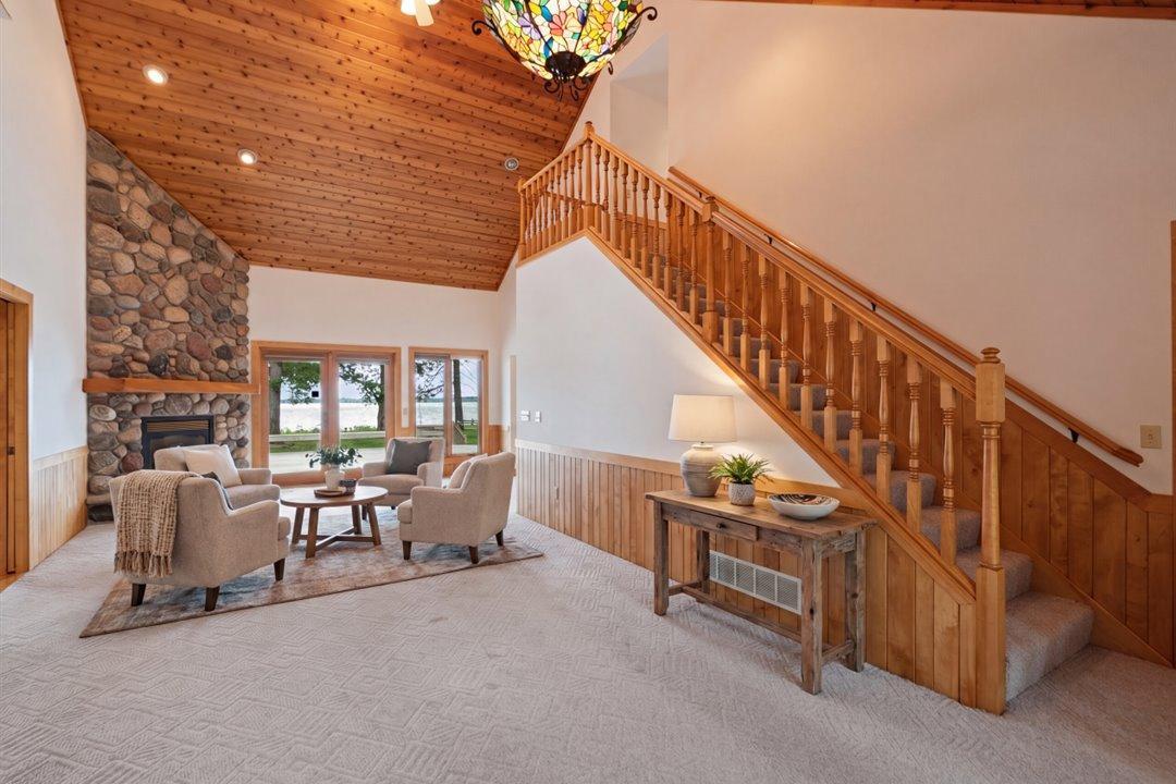 Virtually Staged. A grand staircase, soaring ceilings, and a floor-to-ceiling stone fireplace create a dramatic introduction to this lakeside retreat.