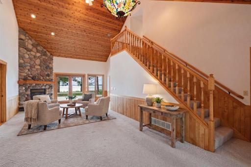 Virtually Staged. A grand staircase, soaring ceilings, and a floor-to-ceiling stone fireplace create a dramatic introduction to this lakeside retreat.