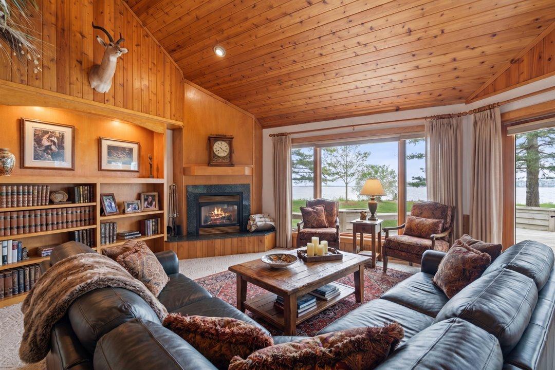 Virtually Staged. Walls of glass frame Upper Whitefish Lake while a fireplace and lakeside deck create an inviting space for year-round enjoyment.