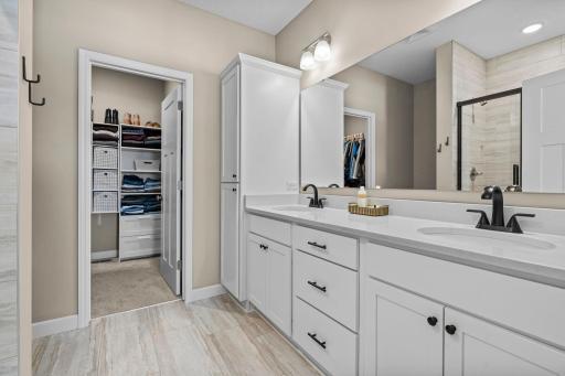 The private primary bathroom has an abundance of storage along with a dual sink vanity, and a tiled shower.