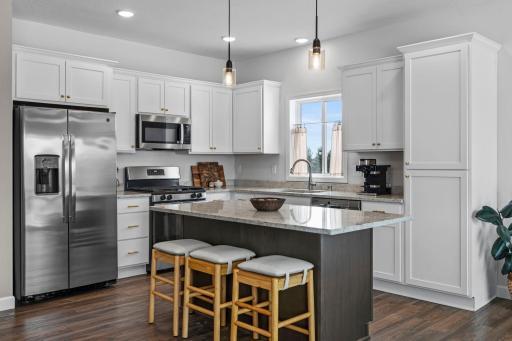 The kitchen gleams with its two toned cabinets and seating for four at the island.