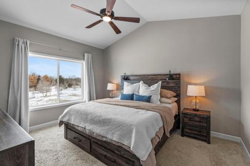 The main level primary bedroom features a vaulted ceiling and has a front row seat to all of the beautiful foliage in your backyard.
