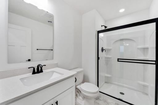 This lower-level bathroom includes a stylish vanity and a glass-enclosed shower