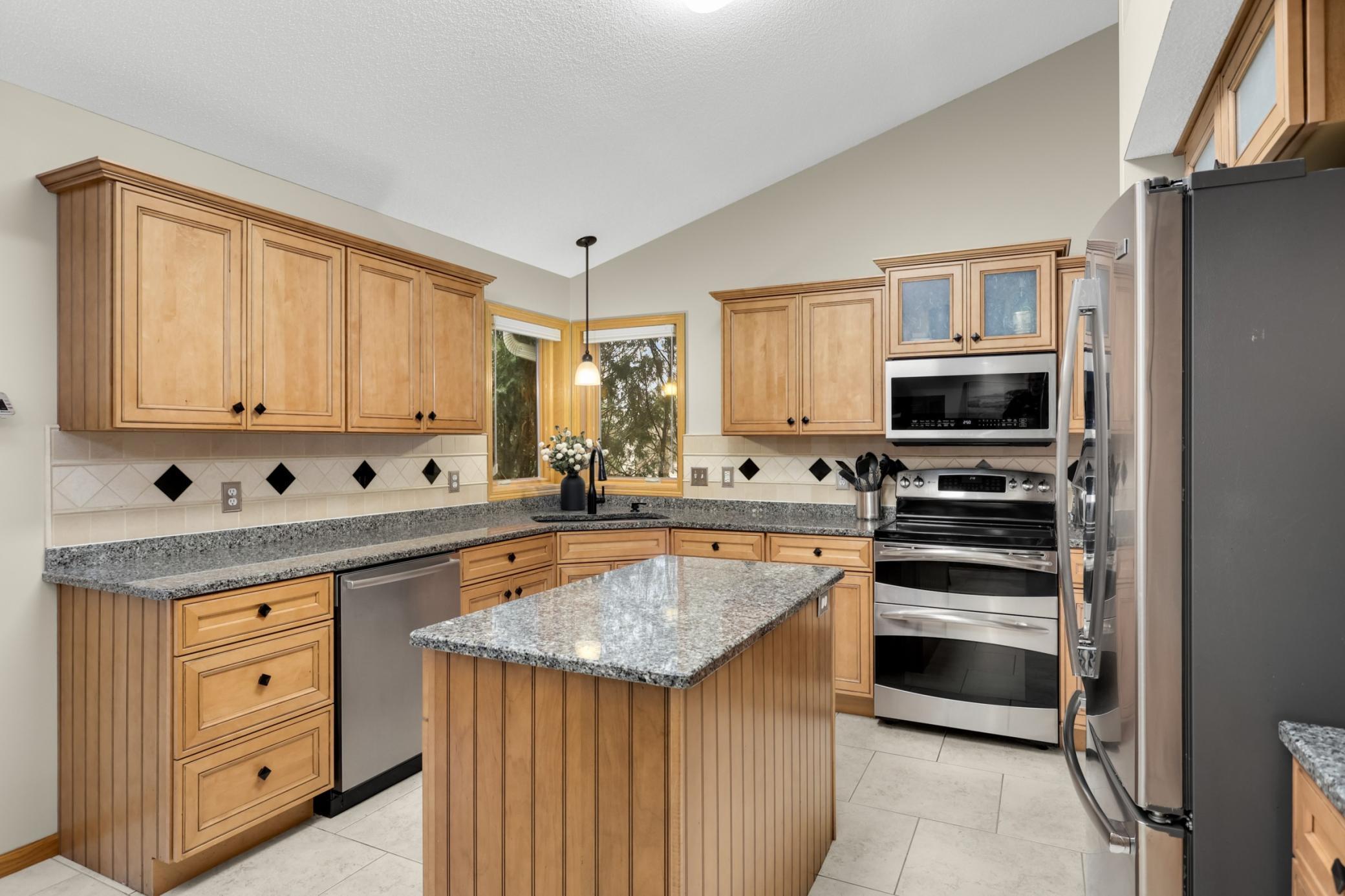 Functionally designed kitchen includes custom cabinets with oversized drawer storage, organizational features, vaulted ceilings, decorative niche, stainless steel appliances, a popular dual kitchen window.