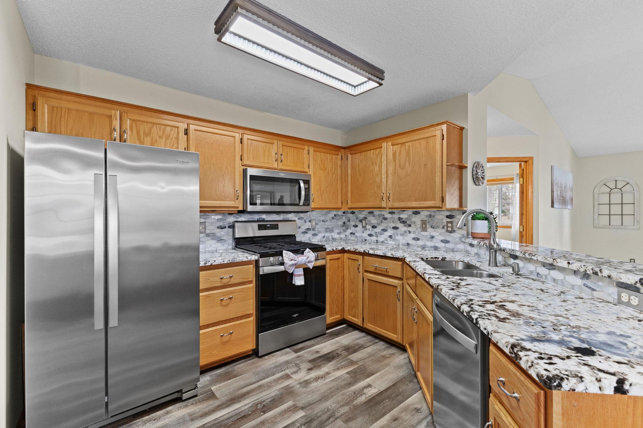 This updated kitchen features thick-cut granite countertops, tile backsplash, stainless steel appliances, and updated lighting.