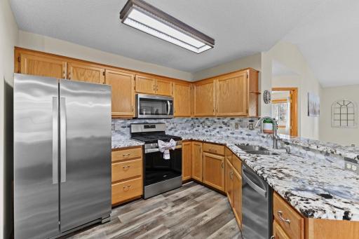 This updated kitchen features thick-cut granite countertops, tile backsplash, stainless steel appliances, and updated lighting.