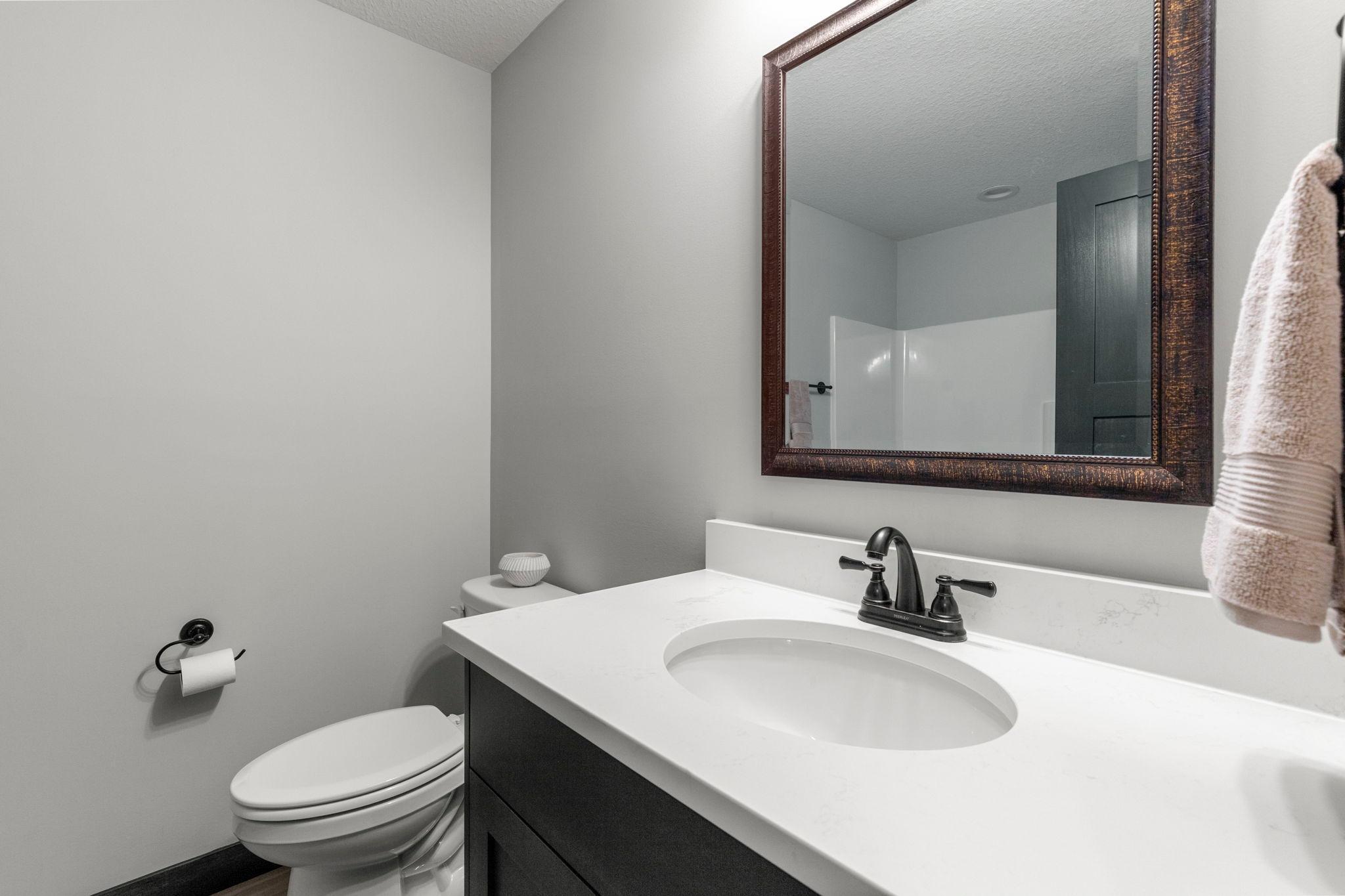 Large full bathroom with beautiful tiled flooring and fixtures. Quartz countertops.