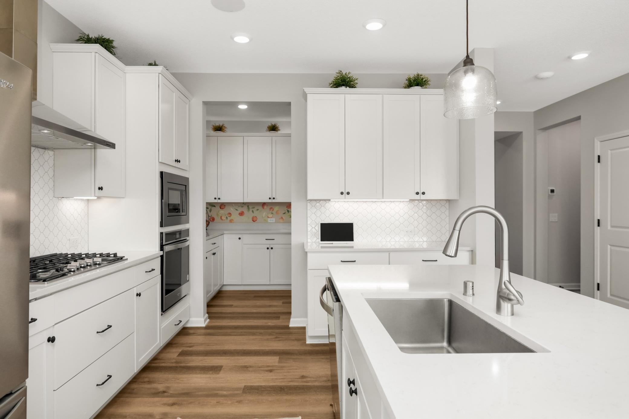 This angle shows the butler pantry which leads to a huge walk-in pantry! Note the cabinets are upgraded with soft close drawers and hidden trash/recycling.