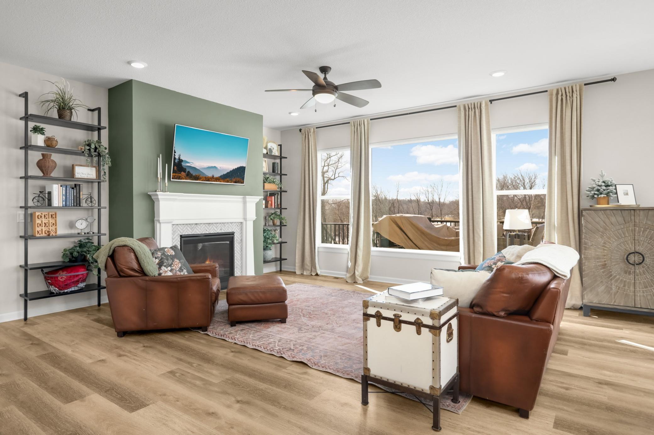 The heart of the home, the main level family room with tall ceilings, ceiling fan, gas fireplace and large southwest facing windows for afternoon sun.