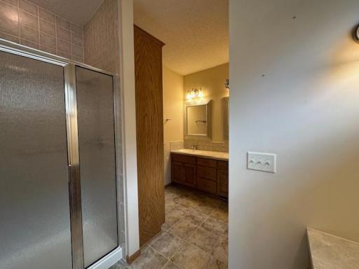 Shower and private toilet area in primary bath with double sinks and added cabinetry