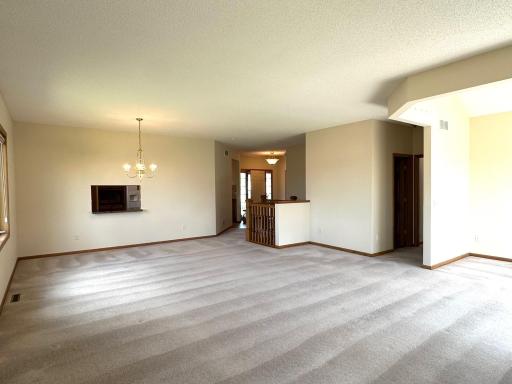 Looking back to the entry way and hallway leading to primary suite. Handy window in kitchen to pass through or serve items to the dining room area.
