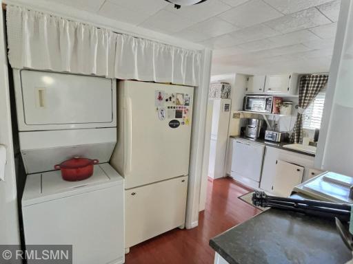Stackable washer dryer and refridgorator near kitchen.