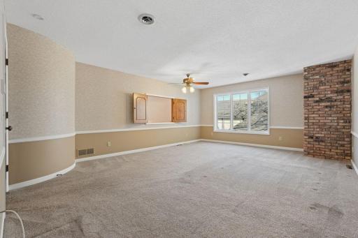 âSpacious primary bedroom featuring a large picture window, brick accent wall, neutral carpeting, and an expansive layout with room for a sitting area or office setup.â