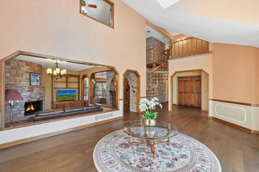 âElegant front living area with Tuscan-inspired arches, rich brick and wood details, and a graceful curved staircase showcasing exceptional craftsmanship and warm architectural character.â