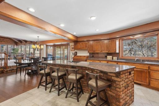 âOpen kitchen with warm wood cabinetry, a large brick-front island with seating, and expansive views to the dining area and four-season porchâan ideal layout for everyday living and entertaining.â