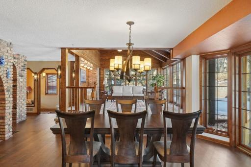 âOpen dining area with large windows and warm wood floors, offering seamless flow into the four-season porch and views toward the brick arched bar areaâan inviting setting for everyday meals and entertaining.â