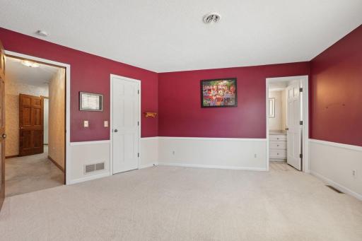 âSpacious bedroom featuring bold two-tone walls with classic wainscoting, neutral carpeting, and direct access to a private bath, with plenty of room for a larger furniture layout.â