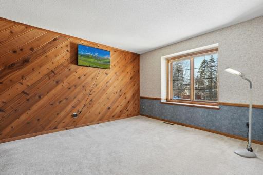 âBedroom with a large window overlooking the yard, featuring a unique wood-accent wall, neutral carpeting, and ample space for furnitureâan inviting and versatile room on the upper level.â