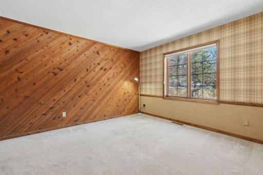 âBright bedroom featuring a large window with views of the yard, warm wood-accent wall, neutral carpeting, and ample space for furnitureâan inviting upper-level room.â