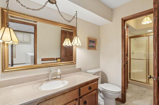 âConvenient bath off the hot tub room, featuring a spacious vanity with warm wood cabinetry, large framed mirror, pendant lighting, and a separate showerâideal for easy post-spa use.â