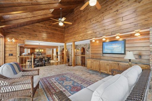 âSpacious four-season porch with vaulted wood ceilings, brick flooring, and abundant windows, offering warm natural light and an open view into the kitchen and bar area for effortless entertaining.â