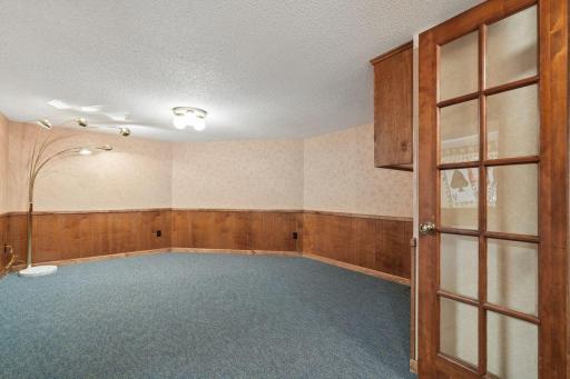 âLower-level rec room with wood wainscoting, neutral walls, and a spacious open layoutâideal for games, media, or a hobby space.â