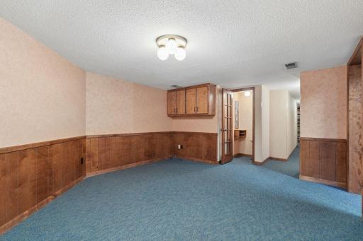 âLower-level rec room with wood wainscoting, neutral walls, and flexible open space, plus a small alcove that once served as a phone-call closetâideal for storage or a compact workspace.â