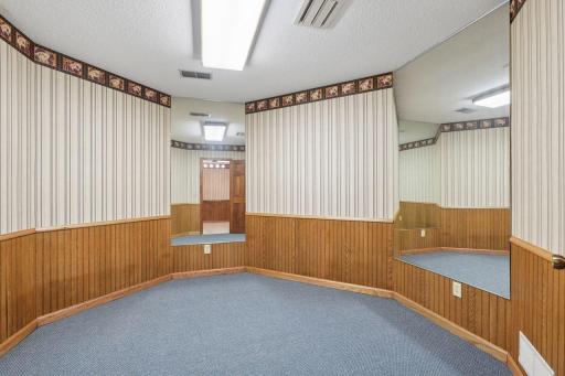 âLower-level flex room with wood wainscoting, mirrored accent walls, and an open layoutâideal for a workout area, dance space, hobby room, or additional recreation zone.â