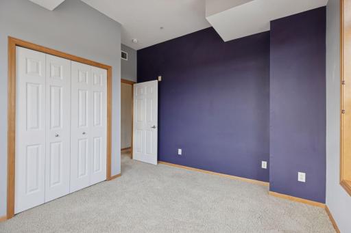 Bright secondary bedroom featuring high ceilings, large corner windows, and beautiful natural light with scenic views.