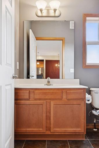 Bathroom vanity with expansive mirror, updated lighting, and additional storage below.