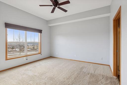 Primary bedroom with with high ceilings, ensuite bathroom, and expansive window offering beautiful views and a bright, airy feel.