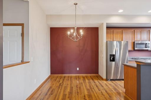 Spacious dining space conveniently located off the kitchen, featuring warm wood flooring and stainless steel appliances nearby.